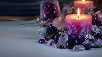 Purple candles burning with amethyst crystals and gemstones creating mystical spa atmosphere for meditation and spiritual healing rituals.