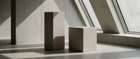 Minimalist geometric paper house model with clean shadows on white surface near window. Modern architectural concept for real estate, home design, construction planning.