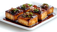 Grilled tofu cubes with teriyaki glaze and fresh herbs on white plate. Asian cuisine, vegetarian protein, healthy cooking for restaurant menus and food blogs.