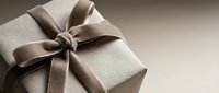 Elegant gift box wrapped in kraft paper with a luxurious satin ribbon bow on a neutral beige background, perfect for holiday and celebration concepts.