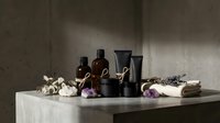 Luxury spa wellness setup with essential oil bottles, candles, towels and lavender flowers on marble surface for relaxation and self-care rituals.