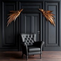 Luxurious black leather armchair against dark wall with golden metallic wing decorations. Modern interior design with classic furniture and dramatic lighting.