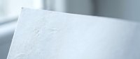 Close-up of white textured paper with embossed surface and soft lighting creating subtle shadows for premium stationery and printing projects.