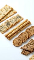 Assorted whole grain crackers and bread slices with seeds and herbs arranged on white background for bakery, nutrition, and healthy eating concepts.