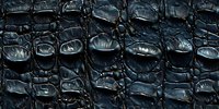 Dark crocodile skin texture with glossy scales in deep blue and black tones creates dramatic natural pattern. Seamless repeat for luxury fashion design.