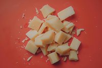 Roughly chopped white chocolate chunks scattered on vibrant red background, creating contrast for food photography and confectionery designs.