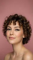 Young woman with curly brown hair and winged eyeliner makeup posing against pink background for beauty and fashion portrait photography.
