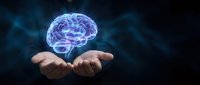 Glowing digital brain hologram floating above open human hands against dark background. Concept of artificial intelligence, neuroscience and mental health innovation.