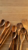 Wooden kitchen utensils and spoons arranged on natural wood table background with copy space for cooking and culinary design projects.