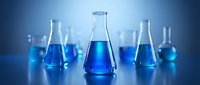 Laboratory glassware with blue chemical solutions on reflective surface for scientific research and experimentation in modern chemistry lab setting.