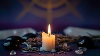 Burning candle with coffee beans, crystals and mystical symbols creating spiritual atmosphere for meditation, divination and esoteric practices.