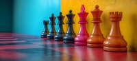 Colorful chess pieces lined up on board showing black and red figures against vibrant yellow and blue background, symbolizing strategy and leadership concepts.