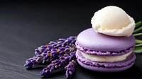 French macarons with lavender flowers on dark slate background. Purple and white almond cookies for bakery, cafe menu, dessert photography, culinary blog.