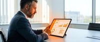 Middle-aged Caucasian businessman analyzing financial data on tablet in modern office with natural lighting for corporate presentations and reports.