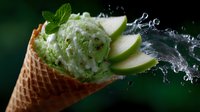 Fresh mint ice cream scoop in waffle cone with green apple slices and water splash on dark background, refreshing summer dessert concept.