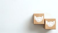 Two wooden blocks with handshake icons on white background representing business partnership, cooperation and agreement concepts for corporate design.