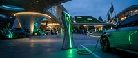 Futuristic electric vehicle charging station with glowing green energy cables and modern architecture at twilight for sustainable transportation concepts.