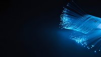 Blue fiber optic cables with glowing light transmission on dark background for technology and communication concepts.
