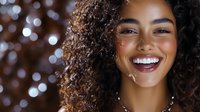 Young African American woman with natural curly hair and bright smile against bokeh lights background, radiating joy and confidence in festive evening setting.
