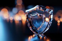 Crystal glass shield symbol on dark background with orange bokeh lights and blue glow, representing digital security and data protection concept.