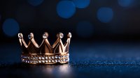 Golden crown with diamonds on dark blue background with bokeh lights, luxury jewelry symbol of royal power and success, close up macro shot.