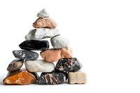 Balanced stack of natural mineral stones and rocks in pyramid shape on white background, isolated composition for wellness and meditation concepts.