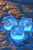 Glowing blue ice cubes with AI text on dark textured surface, illuminated from within creating ethereal light effect against golden bokeh background.