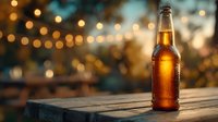 Cold beer bottle with condensation on wooden table against blurred bokeh lights background at sunset, perfect for beverage advertising.