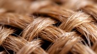Extreme close up macro shot of woven natural brown rope or twine texture showing detailed fiber strands and weaving pattern. Suitable for backgrounds and textures.