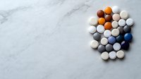 Colorful pharmaceutical pills and tablets arranged on light marble background, top view composition with copy space for medical and healthcare concepts.
