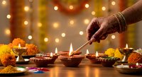 Woman lighting traditional oil lamps during Diwali celebration with marigold flowers and warm bokeh lights creating festive Hindu festival atmosphere.