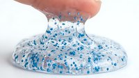 Stretchy slime with blue glitter and foam beads being pulled upward, isolated on white background for craft projects and sensory toy design.
