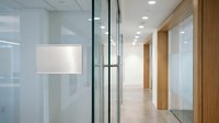 Modern office interior with glass walls and wooden accents creating bright professional workspace for corporate business environment.