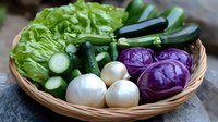 Fresh organic vegetables in wicker basket including lettuce, zucchini, cucumber, white onions and purple cabbage for healthy cooking and farm to table meals.
