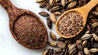 Ground flaxseed and pink salt in wooden spoons with scattered flax seeds on white background, healthy organic superfood ingredients for cooking.