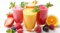 Fresh fruit smoothies in tall glasses garnished with mint leaves and surrounded by strawberries, raspberries, blackberries and orange slices on white background.