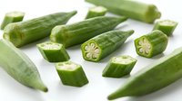 Fresh green okra pods whole and sliced showing seeds, healthy organic vegetable ingredient for cooking and nutrition on white background.