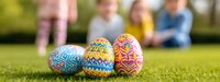 Colorful decorated Easter eggs on green grass with blurred family in background enjoying spring holiday celebration outdoors.