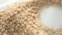 Raw quinoa seeds scattered on white surface showing organic superfood grain texture and natural healthy cooking ingredient for nutritious meals.