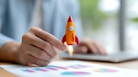 Orange rocket with flame trail held over business charts and graphs on desk, symbolizing startup growth and business success metrics analysis.