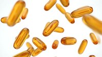 Golden omega-3 fish oil capsules scattered on white background. Dietary supplements for heart health, brain function and wellness nutrition.