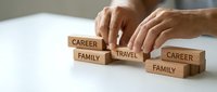 Hands balancing wooden blocks labeled career, family, and travel representing work-life balance and priority management decisions in modern lifestyle.
