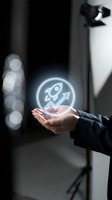 Businessperson holding glowing holographic rocket icon with upward arrow symbol, representing startup growth, innovation, and business success in digital technology environment.