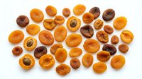 Halved and whole dried apricots scattered on white background, showing golden-orange flesh and dark pits, suitable for food photography, nutrition content, healthy snacking, recipe blogs, and culinary design projects.