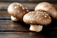 Fresh brown mushrooms with salt crystals on dark wooden surface, macro food photography with selective focus and natural lighting.