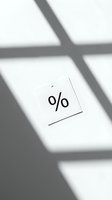 Percent sign on a white price tag with dramatic window shadows, minimal monochrome concept for sale, discount, and finance themes.