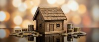 Wooden miniature house model surrounded by stacks of coins on reflective surface with warm bokeh background for real estate investment concepts.