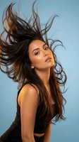 Young Hispanic woman with long brown hair flowing in motion against blue background for beauty and haircare advertising campaigns.