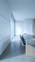Modern minimalist dining room with concrete floors and large windows showcasing clean architectural lines and natural light for contemporary interior design.
