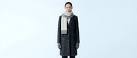 Young woman with East Asian ethnicity wearing dark charcoal wool coat, cream turtleneck sweater, and gray scarf against white background. Professional fashion and lifestyle stock.
